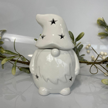 White ceramic gnome with star designs on a gray background