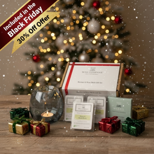 Wax melt gift set with decorative candles and small presents in front of a Christmas tree.