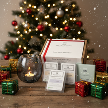 Wax Company gift set with candles and small boxes in front of a decorated Christmas tree.