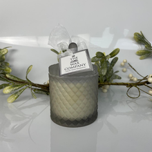 Candle in a textured container with a tag on a white background with decorative elements