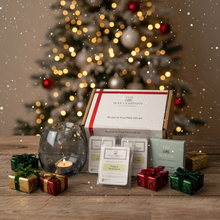 Wax melt gift set with decorative candles and small presents in front of a Christmas tree.