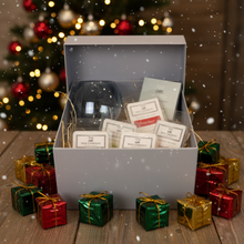 Gift box with wine glasses and cards in front of a Christmas tree