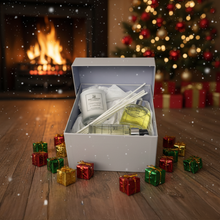 Gift set with diffuser, candles, and reeds on a wooden floor with Christmas decorations.